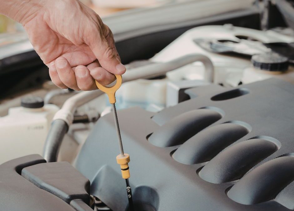Fuga de aceite en el motor de un coche con manchas visibles y revisión mecánica en taller profesional